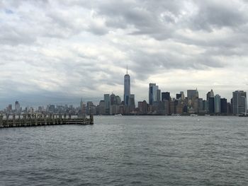 City at waterfront against cloudy sky