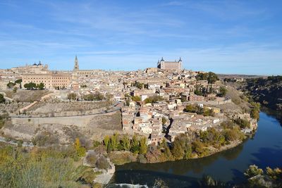 View of castle by river against blue sky