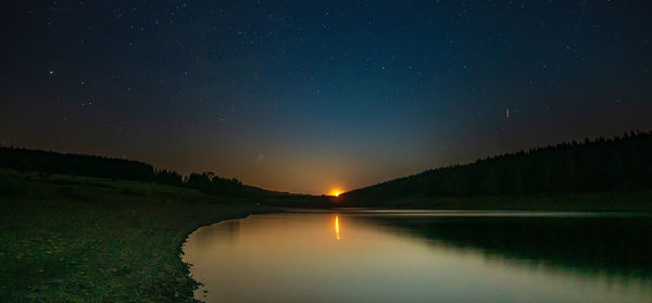 Scenic view of lake against sky at night