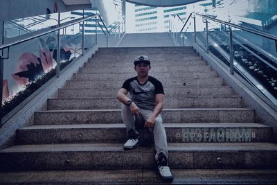 Full length portrait of young man sitting on staircase