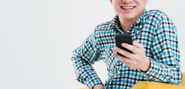 Low angle view of woman using mobile phone against white background