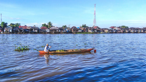 Man sitting on boat in river against sky