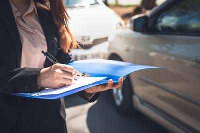 Midsection of businesswoman using mobile phone while sitting on road