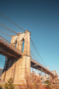 View of brooklyn bridge against clear blue sky during sunny day