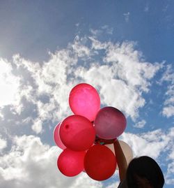 Low angle view of red balloons against cloudy sky