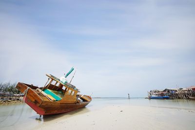 Boat moored on beach against sky