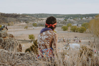 Rear view of woman standing on field against sky