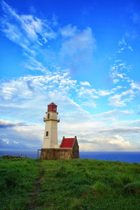 Lighthouse on field against sky