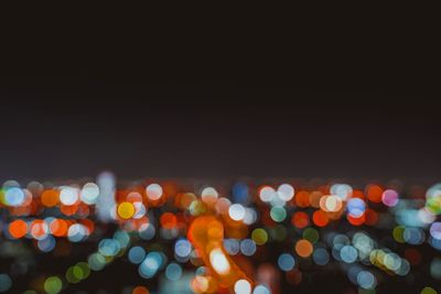 Defocused image of illuminated lights on street at night