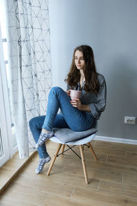 Millennial brown-haired girl drinking tea with cakes alone