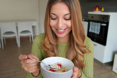 Teenage girl eating muesli granola oatmeal with fruits and yogurt