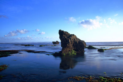 Rock formation on beach against sky