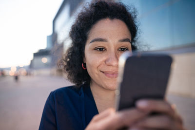 Smiling businesswoman using smart phone at footpath