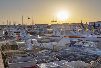 Sailboats moored at harbor during sunset