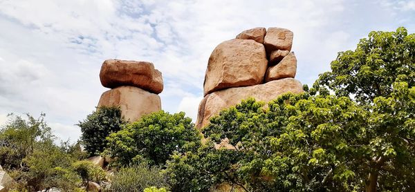 Low angle view of rocks and trees against sky