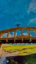 Low angle view of man by sea against blue sky
