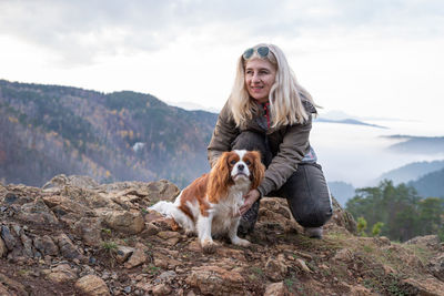 Blond woman and her cavalier king charles spaniel on a mountain top on a hazy day