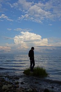 Rear view of man standing at beach against sky