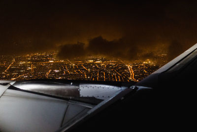 Aerial view of illuminated cityscape seen through airplane window