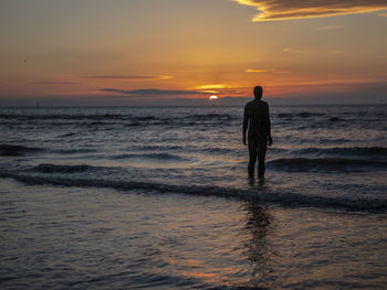 Silhouette man standing on beach during sunset