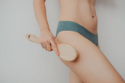 Woman's arm holding dry brush to top of her leg, cellulite treatment and dry brush. high quality