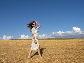 Full length of woman standing on field against sky