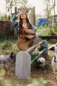 Side view of woman using mobile phone while sitting on grassy field