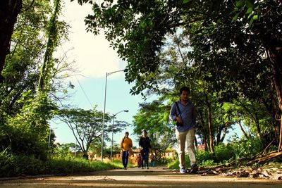 Rear view of men walking on footpath in park