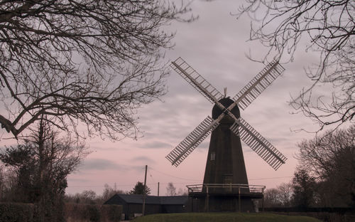 Low angle view of windmill on field against sky