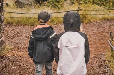 Rear view of siblings walking on field