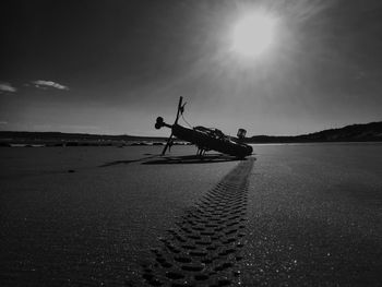 Bicycle on beach against sky during sunset