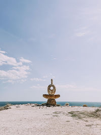 Rear view of woman sitting on beach against sky