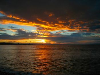 Scenic view of sea against dramatic sky during sunset