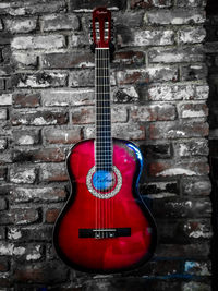 Close-up of guitar against brick wall