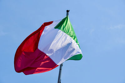 Low angle view of flag against blue sky