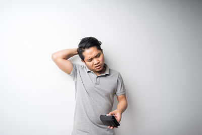 Young man using mobile phone against white background