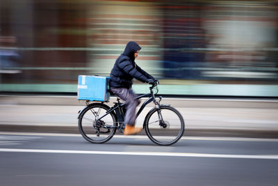 Side view of man riding bicycle on road