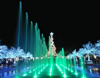 Illuminated christmas tree by swimming pool against clear sky at night