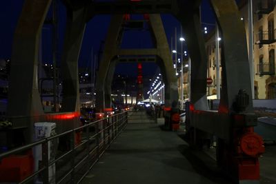 Illuminated footpath amidst buildings in city at night