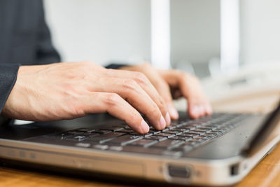 Close-up of man using laptop on table