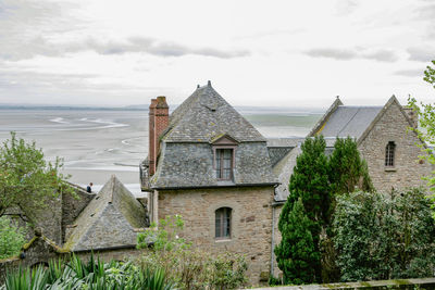 Houses by sea against sky