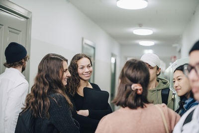 Teenage high school students talking while standing in corridor