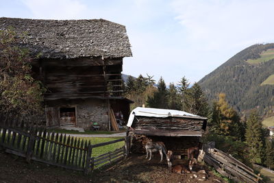 Old wooden house on field against sky