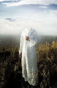 Rear view of woman standing on field against sky