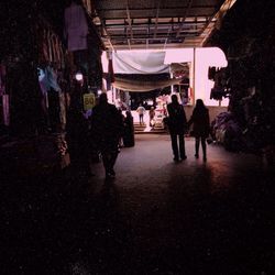 Rear view of people walking in market at night