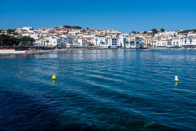 Sea by townscape against clear blue sky