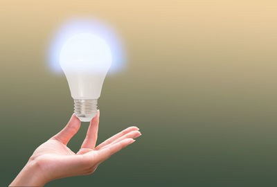 Close-up of woman hand holding illuminated light bulb outdoors