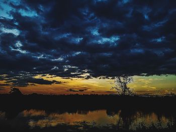 Scenic view of lake against dramatic sky during sunset