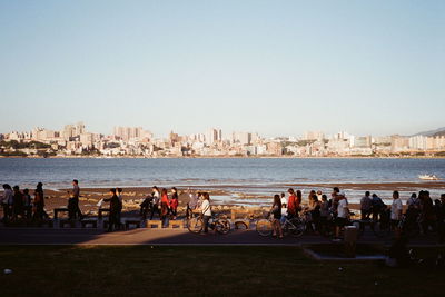 People at beach against clear sky