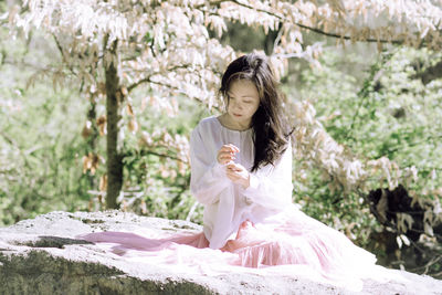 Side view of young woman standing in forest